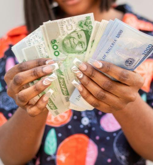 Woman holding several Nigerian Naira notes