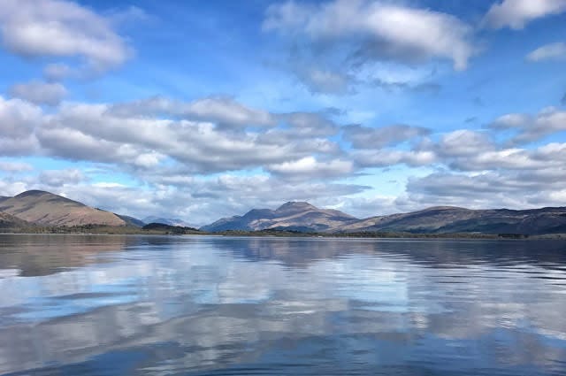 A low shot taken from the waters of Loch Lomond with the sky reflected in the water