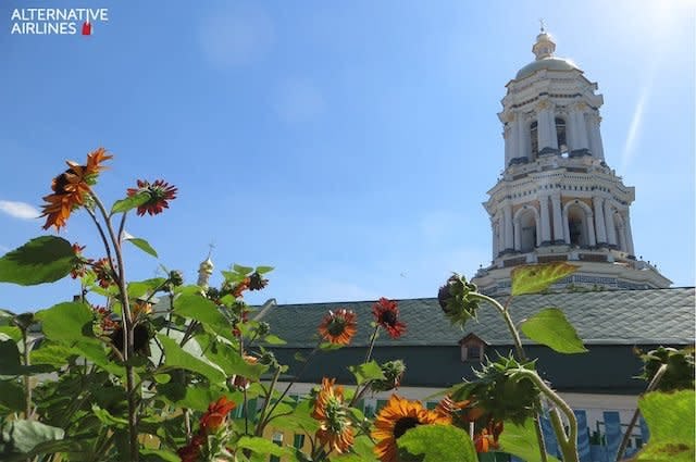 A white Orthodox monastery in Kyiv surrounded by green and yellow sunflowers 