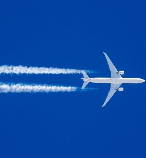 Plane flying through blue sky with jet stream