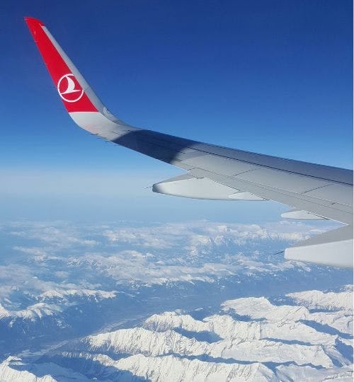 Turkish Airlines wing above snowy mountains