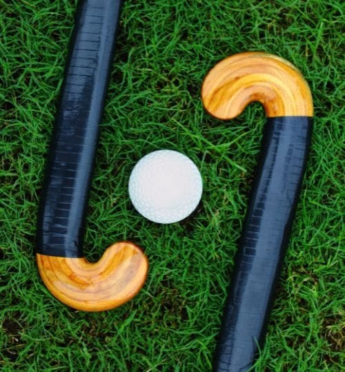 Two hockey sticks and a ball on grass