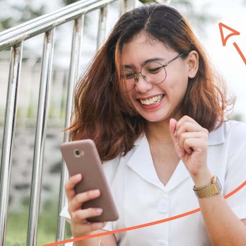 A woman smiling while looking at her phone