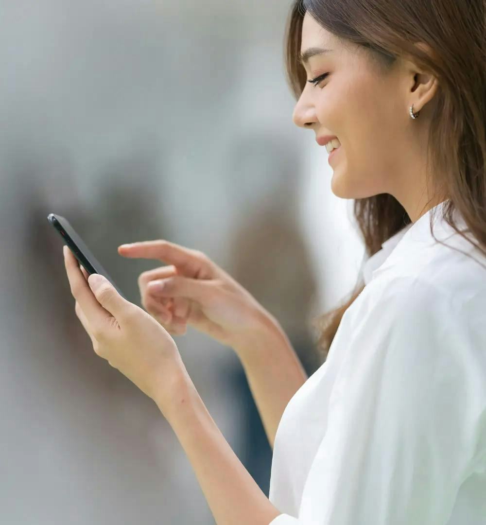 A woman smiling while using her phone