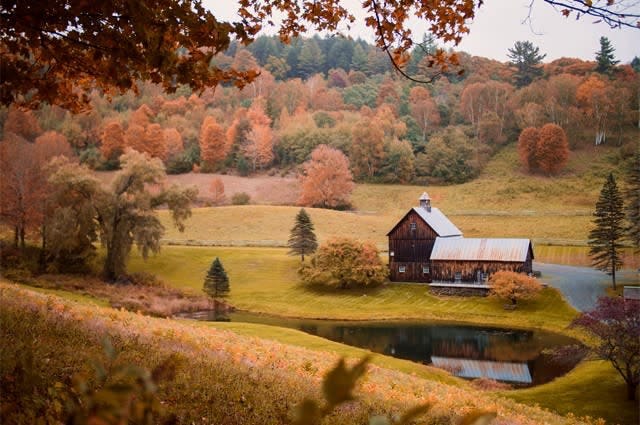 Woodstock, Vermont, with a traditional barn-style home surrounded by Fall colour trees
