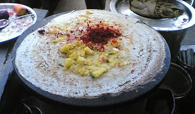 A street food vendor making up a dosa kebab