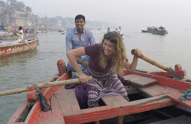 Woman steering river boat with local man on the back of boat