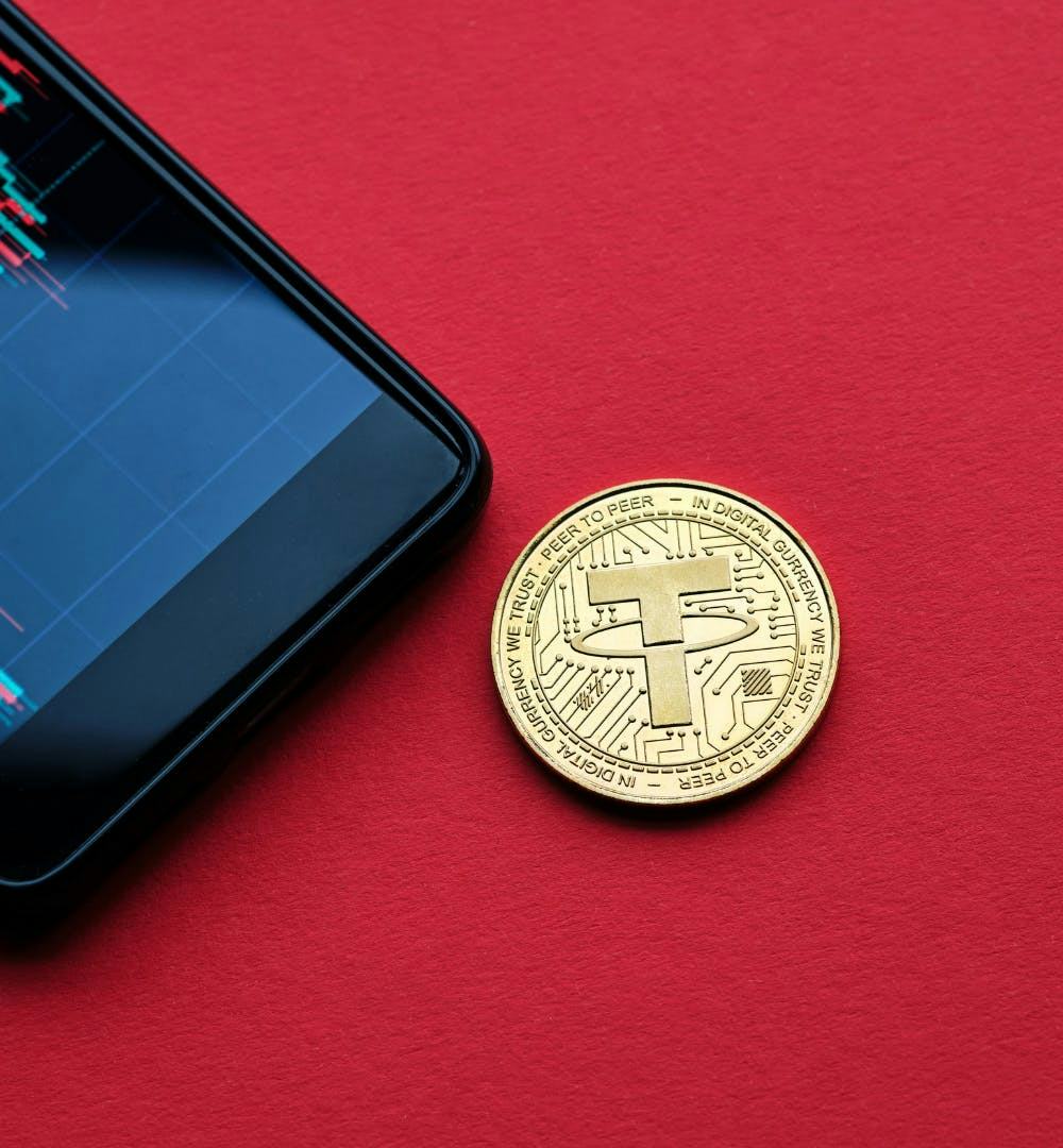 A single Tether coin next to a mobile phone