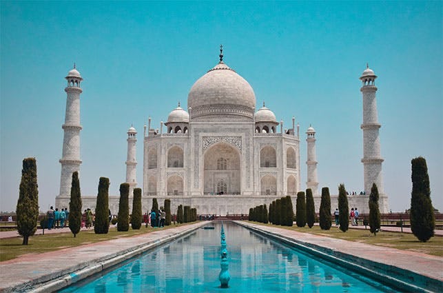 Image of the Taj Mahal in Arga. The Taj Mahal is a white marble building surrounded by pools and gardens.