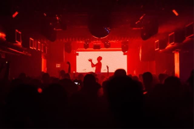 The inside of one of Berlin's many techno clubs with a large crowd and red lights illuminating the room