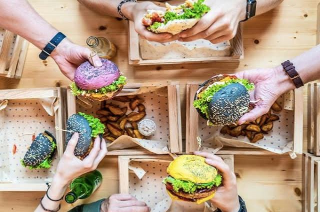 People holding burgers with unique coloured burger buns
