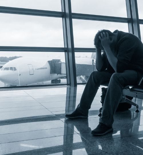Man holding his head while waiting in an airport lounge