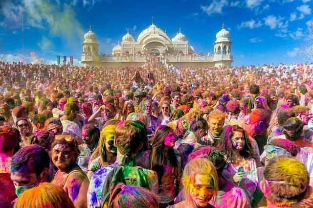 Holi celebrations in India, showing a dense crowd of people covered in coloured paint and powder