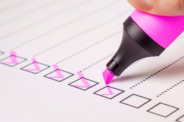 close up of a pink highlighter adding ticks to a checklist
