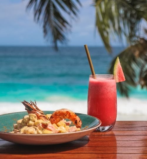 Seafood dish and a cocktail on a beach in Seychelles