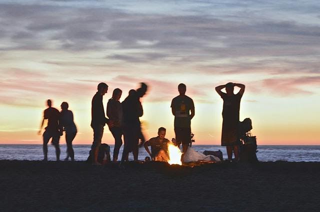 Group of people standing around fire on a beach
