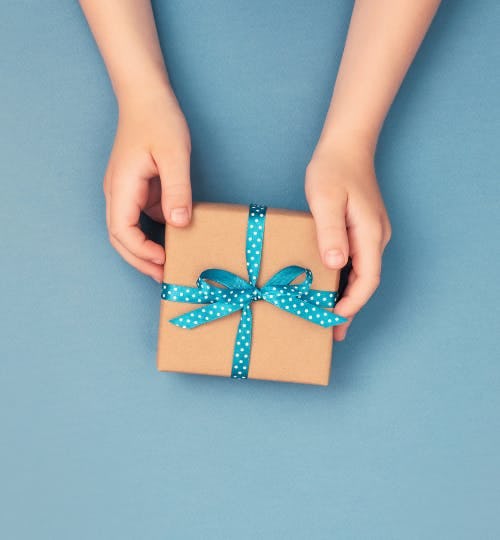 Hands holding a small gift on blue background