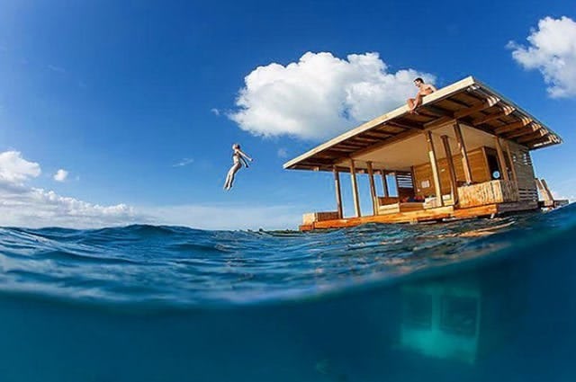 A floating rental accommodation at Manta resort. Customers are jumping off into the calm blue sea
