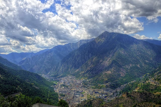 View looking downwards at Andorra la Vella, with green slopes and sunshine