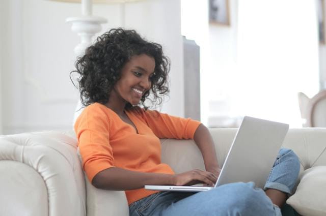 A woman sat on her sofa browsing the internet