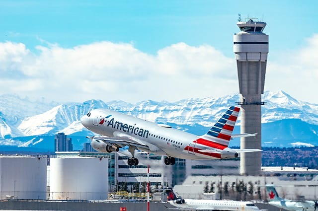 American Airlines plane taking off with mountain ranges and ATC towers in the distance 