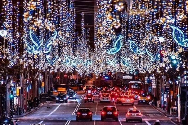 a view down a busy road in Barcelona, taken at night to show the Christmas lights twinkling above the road