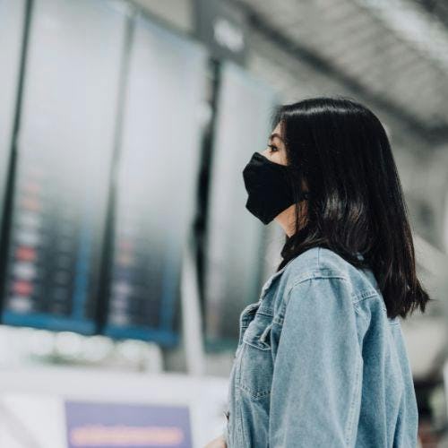 Woman wearing a mask looking at flight schedule