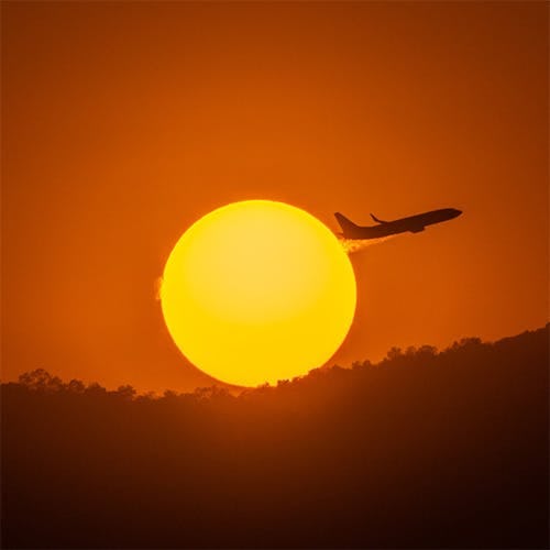 Shadow of an airplane with bright sunset in background