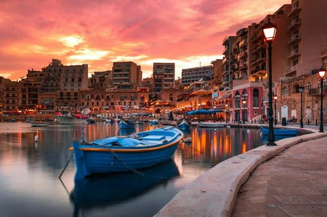 A sunset shot taken at a harbour in Malta with blue rowing boat in the foreground