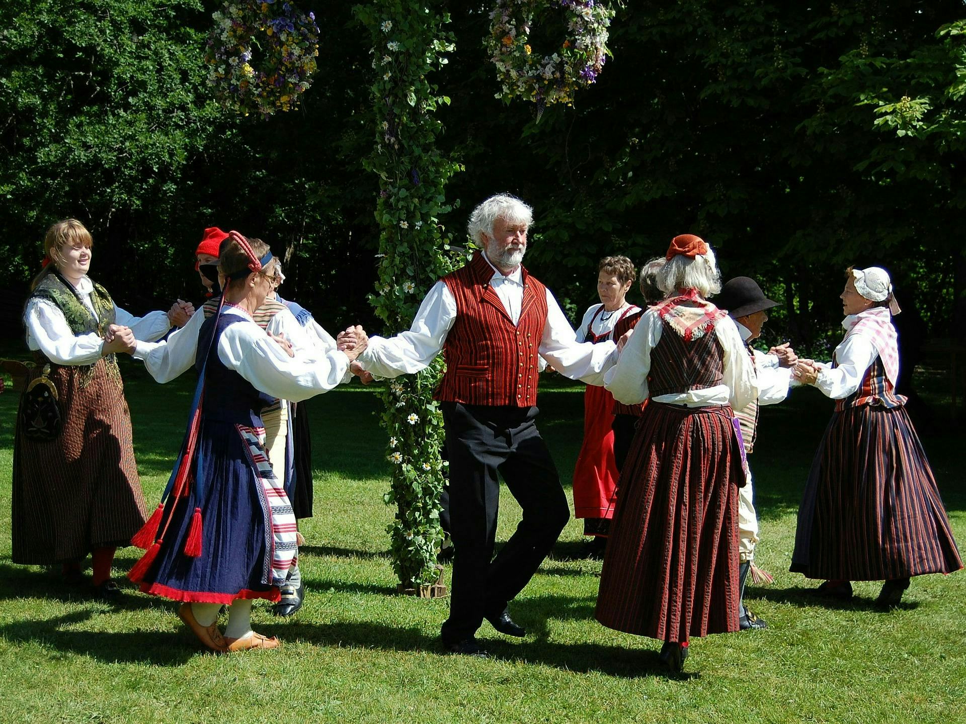 Swedes in traditional dress dancing around the maypole celebrating Midsummer
