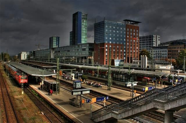 A shot of a German train station taken on a cloudy day. A train is at one of the platforms. 