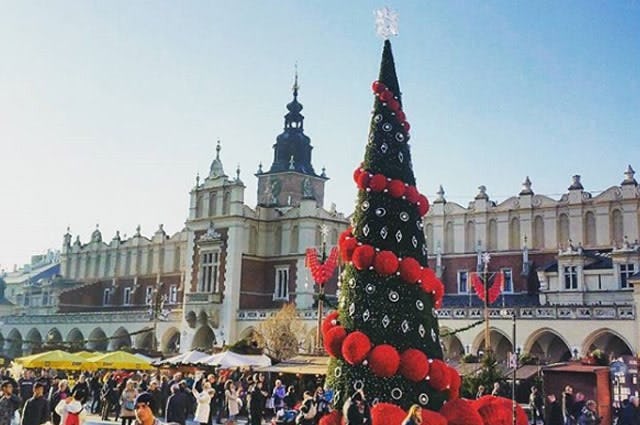 A Christmas market shot taken in Krakow, with a cone shaped tree covered in large red baul bauls in the foreground. 
