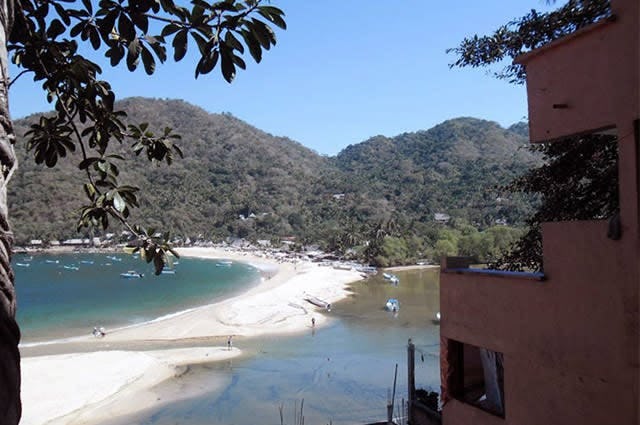 A view from the balcony of a hotel next to Yelapa beach in Mexico, depicting the white sand of the beach and trees