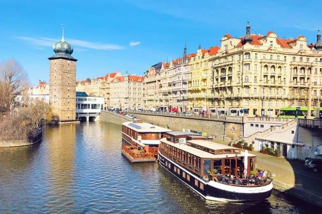A photo of a waterway in Prague with cruise boat and architecture 