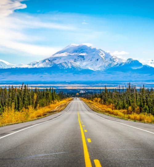 Long road in Alaska with a mountain the background