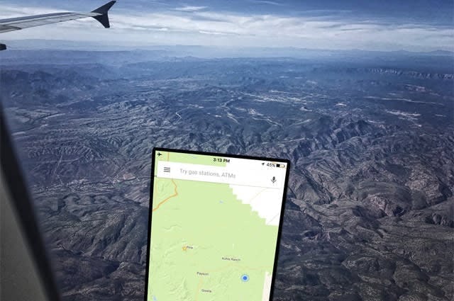 Google maps open on a smartphone in front of an airplane's window inflight over a mountainous landscape