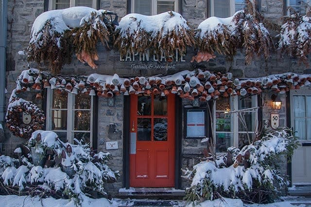A shot of a stone cafe with a red door, covered in snow