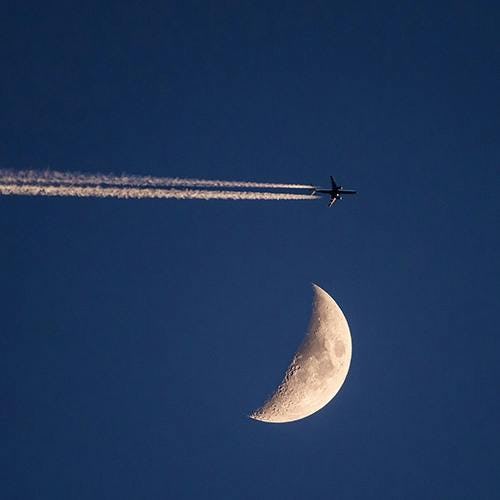 Airplane flying in the sky with moon in the background