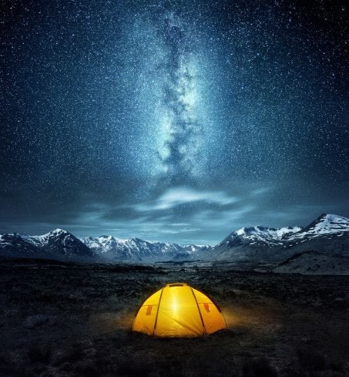 A yellow tent under a starry night sky