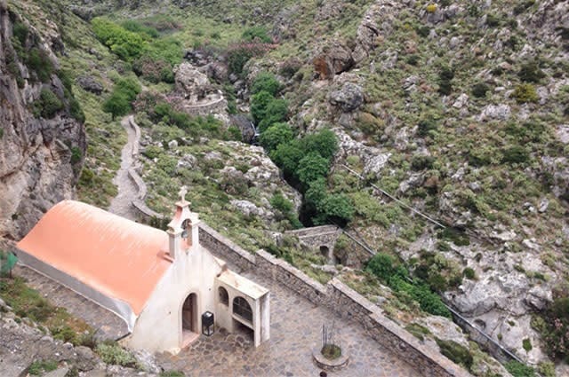 A stone church nestled in the canyon of a mountain range 