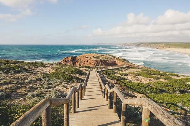 A wooden path leading down to the blue coast of the Portuguese Algarve