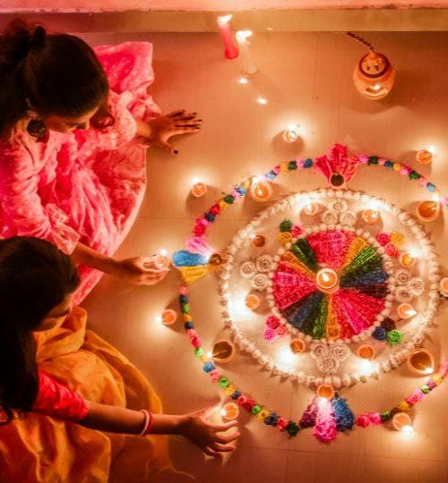 Two women lighting candles for Diwali festival