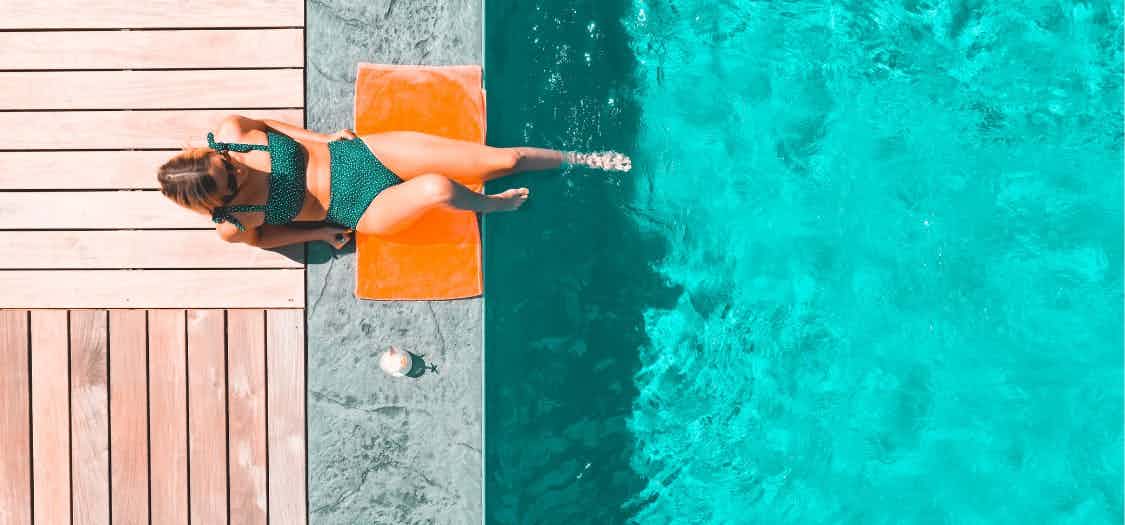 shot looking down at a woman as she sunbaths next to a pool