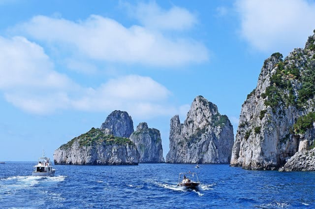 A view of some of the rocks along the Capri coastline and sailing boats 