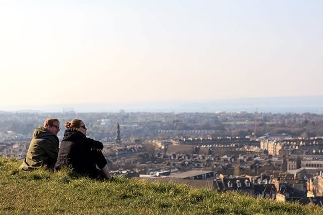 A couple sat on a hill looking over Edinburgh