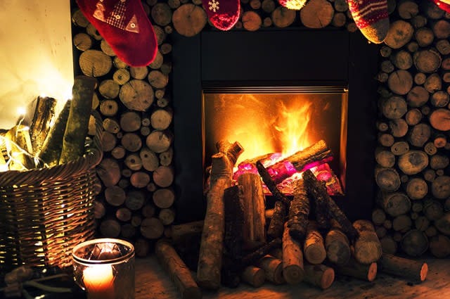Close up photo of a fireplace at Christmas, with a stack of wood and stockings